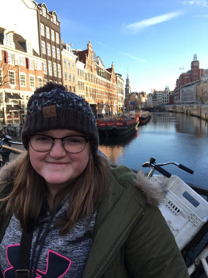 A picture of Bri standing/smiling in front of one of Amsterdam's canals.