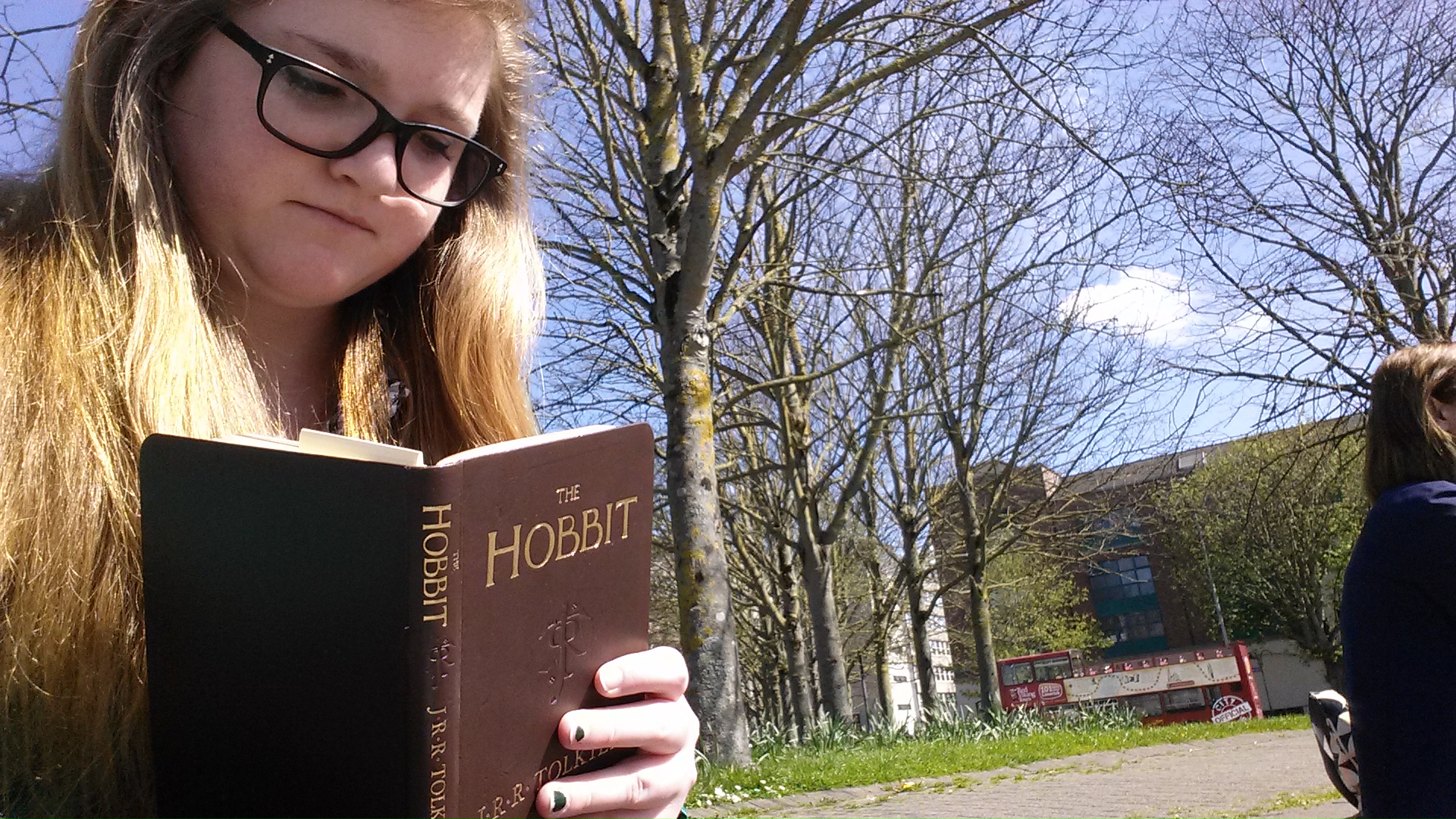 Bri taking a selfie of herself readin her pocket edition of the Hobbit. She is holding the book so that when she looks down at the page she has a double chin and a frown, like an idiot.