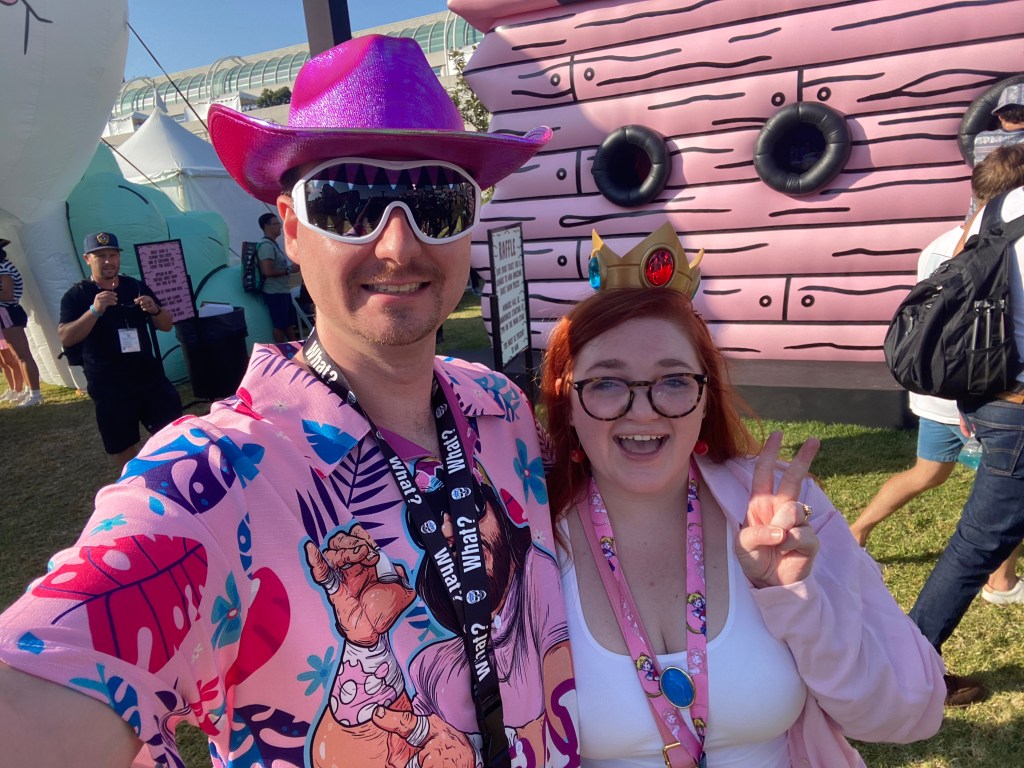 A picture of Bri and Tyler. Bri is dressed as casual Princess PEach with a princess peach crown. Tyler is dressed like Randy Savage with a purple cowboy hat, Randy Savage glasses and a Randy Savage shirt that says "The Cream of the Crop."